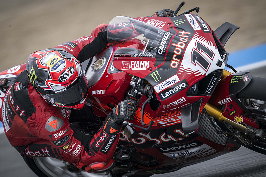 Nicolò Bulega numa curva durante uma corrida do Campeonato de Superbike 2024, pilotando a sua Ducati Panigale V4 R, com o logótipo Magneti Marelli Checkstar visível no capacete.